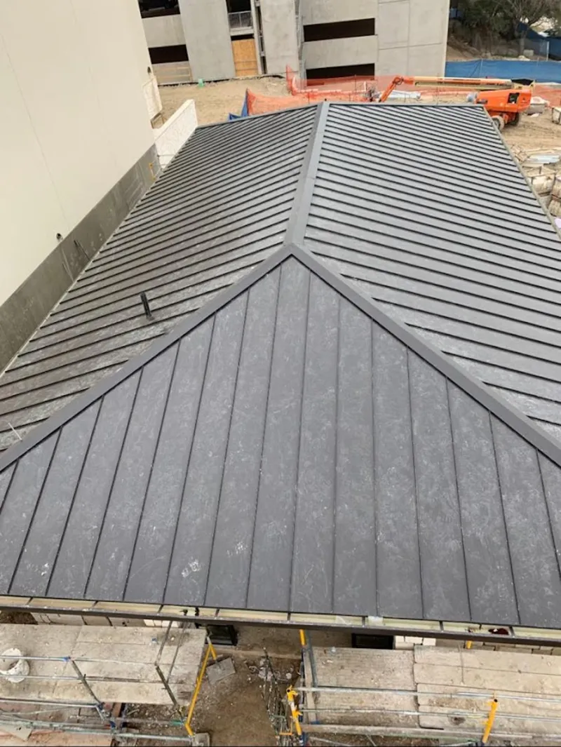 Commercial metal roof construction with crane equipment in Lower Salford